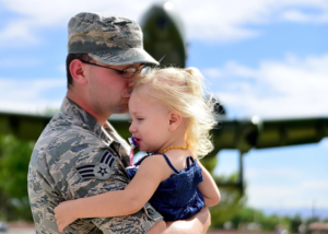 Soldier holding and kissing young girl.