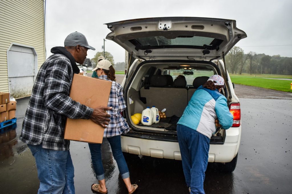 Volunteers loading groceries into the back of a vehicle.